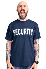 Poster - Young handsome man wearing security t shirt angry and mad screaming frustrated and furious, shouting with anger. rage and aggressive concept.