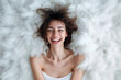 © ADDICTIVE STOCK - Joyful woman lying on a fluffy white surface with a bright smile Generative AI image