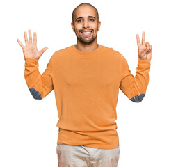 Canvas Print - Hispanic adult man wearing casual winter sweater showing and pointing up with fingers number seven while smiling confident and happy.