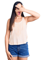 Wall Mural - Young beautiful caucasian woman wearing casual clothes and glasses peeking in shock covering face and eyes with hand, looking through fingers with embarrassed expression.