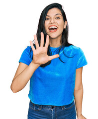 Wall Mural - Young hispanic woman wearing casual clothes showing and pointing up with fingers number five while smiling confident and happy.