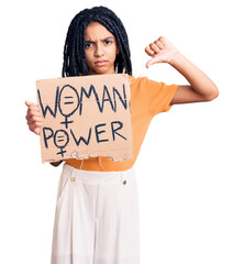 Poster - Cute african american girl holding woman power banner with angry face, negative sign showing dislike with thumbs down, rejection concept