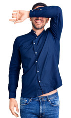 Canvas Print - Young handsome man wearing casual shirt covering eyes with arm smiling cheerful and funny. blind concept.