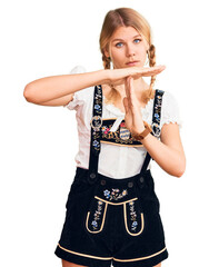 Wall Mural - Young beautiful blonde woman wearing oktoberfest dress doing time out gesture with hands, frustrated and serious face