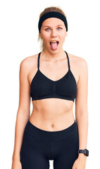 Wall Mural - Young beautiful blonde woman wearing sportswear sticking tongue out happy with funny expression. emotion concept.