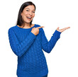 © Krakenimages.com - Young hispanic woman wearing casual clothes amazed and smiling to the camera while presenting with hand and pointing with finger.