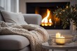 Beige chunky knit throw on grey sofa. Сoffee table with candles against fireplace. 