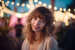 © Pics_With_Love - Radiant young woman with a joyful smile and curly hair, enjoying the enchanting ambiance of an outdoor evening event, illuminated by twinkling lights.