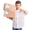 Cute blond kid holding delivery package with angry face, negative sign showing dislike with thumbs down, rejection concept