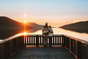 Wall Mural - Couple man and woman hugging  Valentines day family enjoying sunset lake view together travel lifestyle outdoor romantic relationship love concept young lovers walking on pier