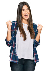 Sticker - Young brunette woman wearing casual clothes screaming proud, celebrating victory and success very excited with raised arms