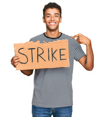 Sticker - Young handsome african american man holding strike banner cardboard pointing finger to one self smiling happy and proud