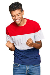 Sticker - Young handsome african american man wearing casual clothes very happy and excited doing winner gesture with arms raised, smiling and screaming for success. celebration concept.