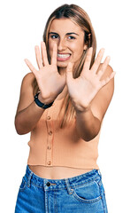 Canvas Print - Hispanic young woman wearing casual summer shirt afraid and terrified with fear expression stop gesture with hands, shouting in shock. panic concept.