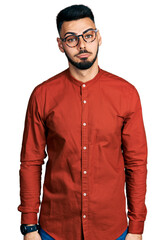 Wall Mural - Young hispanic man with beard wearing business shirt and glasses depressed and worry for distress, crying angry and afraid. sad expression.