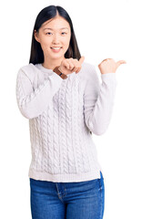 Canvas Print - Young beautiful chinese woman wearing casual sweater pointing to the back behind with hand and thumbs up, smiling confident