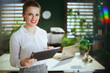 © Alliance - woman real estate agent in green office using digital tablet