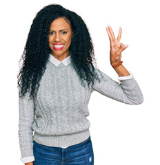 Wall Mural - Middle age african american woman wearing casual clothes showing and pointing up with fingers number three while smiling confident and happy.