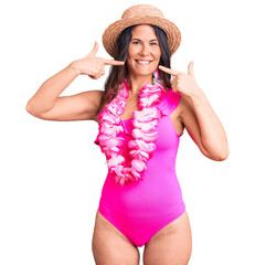 Wall Mural - Young beautiful brunette woman wearing swimwear and hawaiian lei smiling cheerful showing and pointing with fingers teeth and mouth. dental health concept.