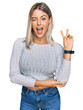 © Krakenimages.com - Beautiful blonde woman wearing casual clothes smiling with happy face winking at the camera doing victory sign with fingers. number two.