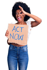 Sticker - Young african american woman holding act now banner smiling happy doing ok sign with hand on eye looking through fingers