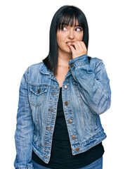 Poster - Young hispanic woman wearing casual clothes looking stressed and nervous with hands on mouth biting nails. anxiety problem.