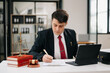 © Nuttapong punna - Mature man lawyer working and gavel, tablet, laptop in front, Advice justice and law concept. at office.