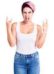 Poster - Young beautiful woman with pink hair wearing casual clothes shouting with crazy expression doing rock symbol with hands up. music star. heavy concept.