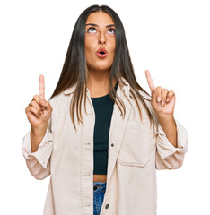 Poster - Beautiful hispanic woman wearing casual clothes amazed and surprised looking up and pointing with fingers and raised arms.