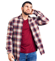 Wall Mural - Young handsome man wearing casual shirt confuse and wondering about question. uncertain with doubt, thinking with hand on head. pensive concept.