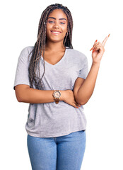 Wall Mural - Young african american woman with braids wearing casual clothes smiling happy pointing with hand and finger to the side