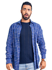 Poster - Young hispanic man wearing casual clothes in shock face, looking skeptical and sarcastic, surprised with open mouth