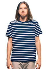 Poster - Handsome caucasian man with long hair wearing casual striped t-shirt puffing cheeks with funny face. mouth inflated with air, crazy expression.