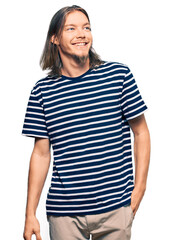 Wall Mural - Handsome caucasian man with long hair wearing casual striped t-shirt looking away to side with smile on face, natural expression. laughing confident.