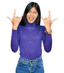 Canvas Print - Beautiful young asian woman wearing casual clothes shouting with crazy expression doing rock symbol with hands up. music star. heavy music concept.