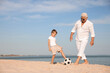 © New Africa - Cute little boy and grandfather playing with soccer ball on sea beach