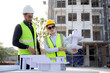 © NT_studio - Team architect and builder talking and holding model house at construction site, contractor and worker discussion and planning strategy about progress infrastructure of real estate, engineer concept.