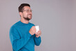 © New Africa - Portrait of happy man holding white mug on grey background. Space for text