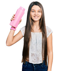 Canvas Print - Young brunette girl with long hair holding shampoo bottle looking positive and happy standing and smiling with a confident smile showing teeth