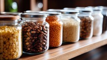 Closeup Of A Collection Of Glass Jars Filled With Bulk Pantry Staples Like Rice, Beans, And Nuts.