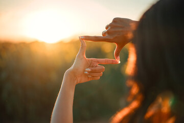 Closeup of woman hands making frame gesture with sunset, Female capturing the sunrise. Future planning concept.