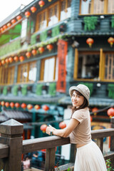 Wall Mural - woman traveler visiting in Taiwan, Tourist with hat sightseeing in Jiufen Old Street village with Tea House background. landmark and popular attractions near Taipei city . Travel and Vacation concept