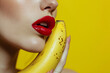 © Keitma - Sexy model woman with red lips make-up taking a bite from yellow banana with the fruit next to her beautiful face