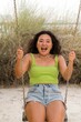 © sashapritchard - Asian woman sitting on the swings against yellow wall background