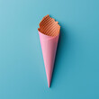 Waffle ice cream cone wrapped in pastel pink color paper against blue background. Copy space. Minimal concept.