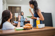 © Odua Images - three Asian girls joke while making breakfast and eating together in the kitchen