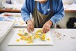 © OMD - artisan pressing flowers into handmade paper sheets