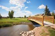 brick footbridge over prairie stream with wooden handrails