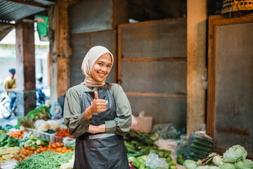 Wall Mural - asian hijab vegetable seller standing and smiling with thumb up gesture