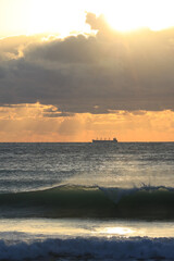 commercial cargo ship sailing in the sun and dark clouds